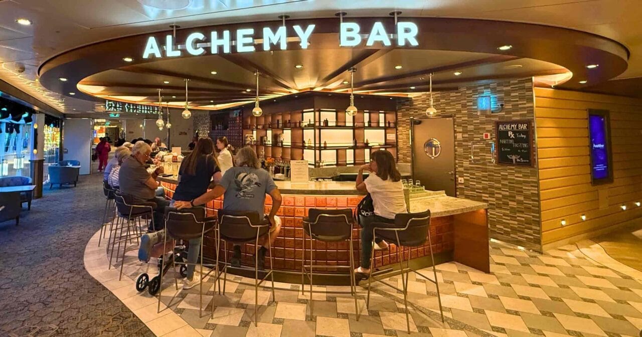 Passengers sitting at the Alchemy Bar on a Carnival cruise ship, a popular venue for using the Carnival drink package.